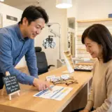 眼鏡店で男性の専門スタッフが40代のお客様に老眼鏡を始めるベストタイミングについて優しく説明している相談風景