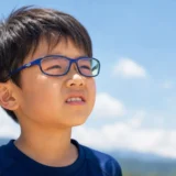 屋外で目への紫外線対策としてUVカットメガネをかける子ども